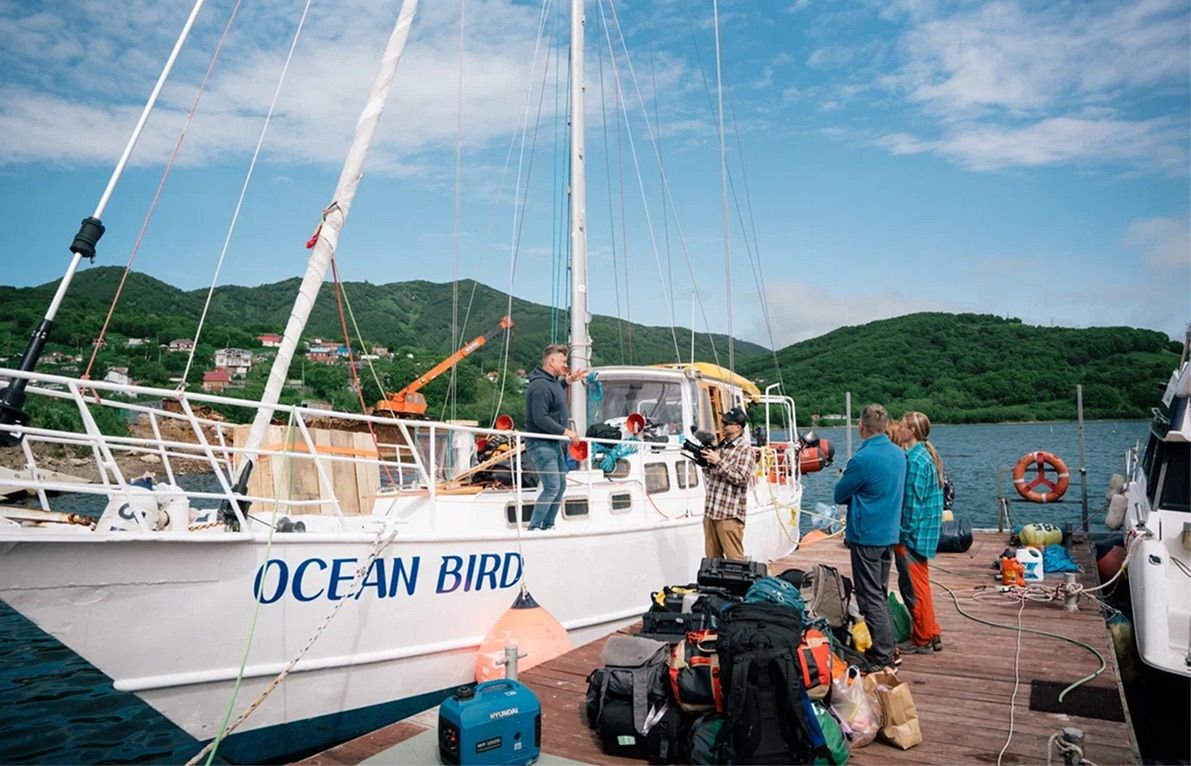 Ocean Bird у деревянного пирса, гости грузят рюкзаки на борт перед выходом