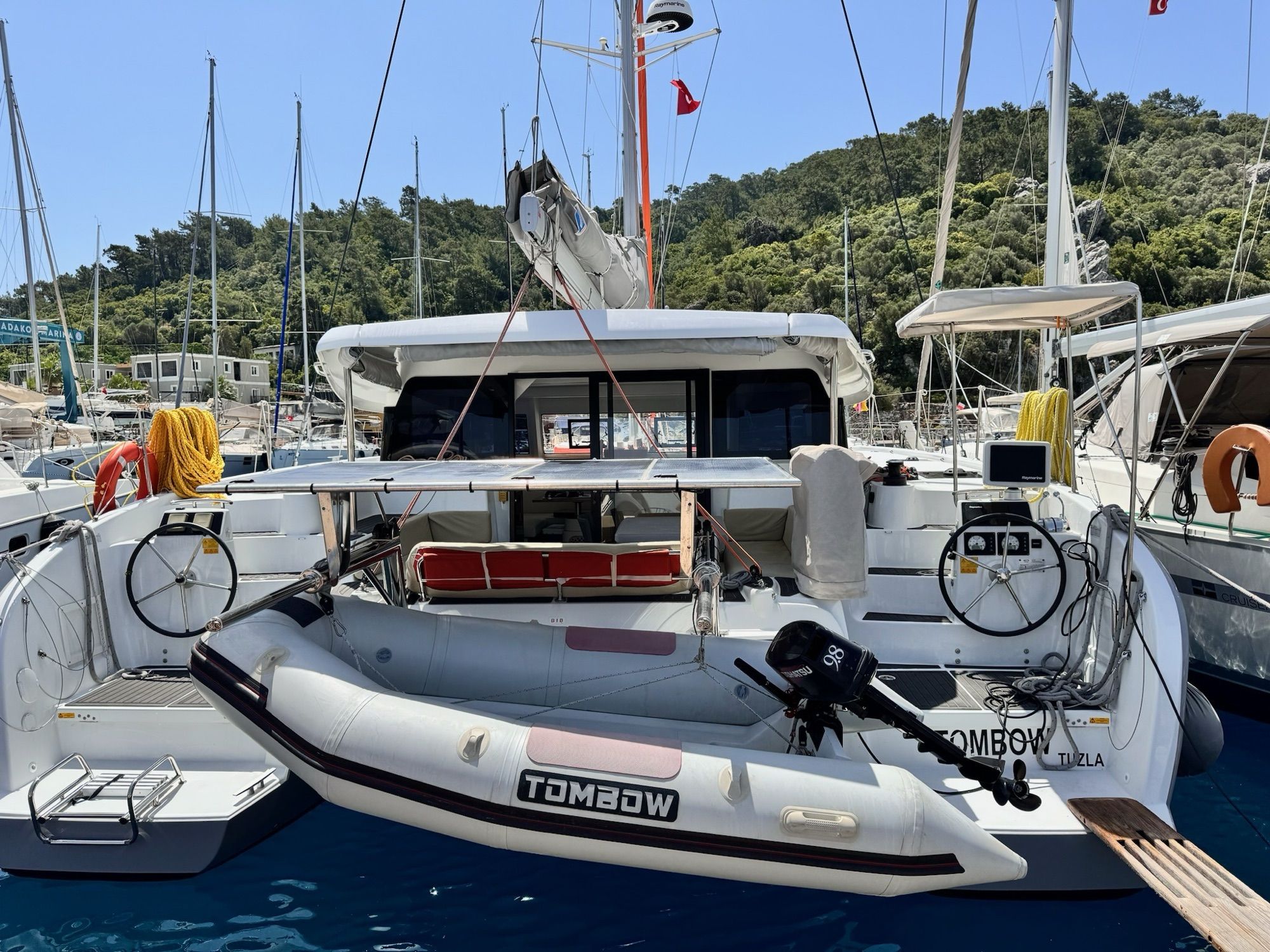 Катамаран Excess 11 «Tombow» кормой к причалу, два штурвала и тузик с мотором