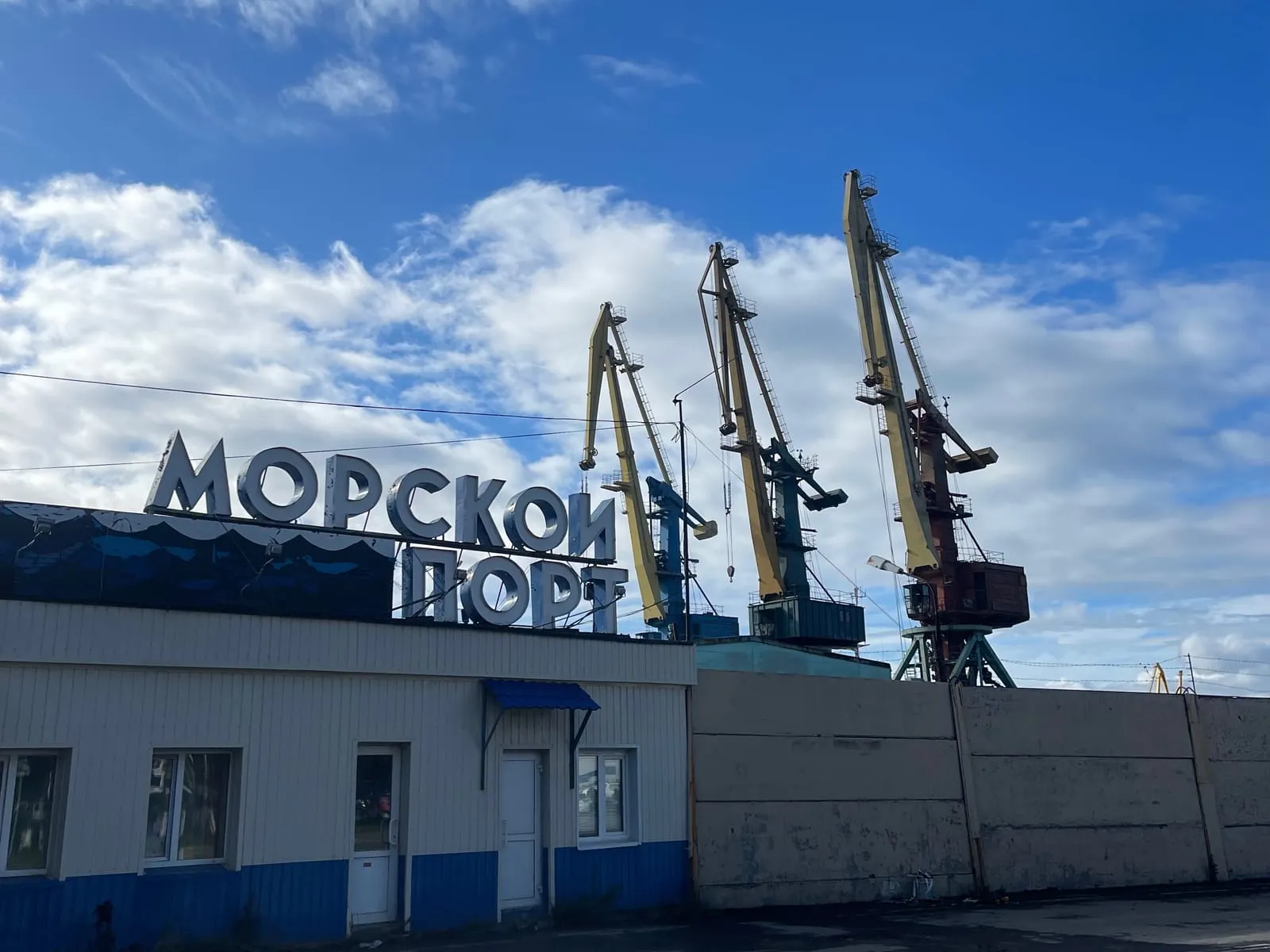 Вывеска «Морской порт» и портовые краны Петропавловска-Камчатского на фоне облаков