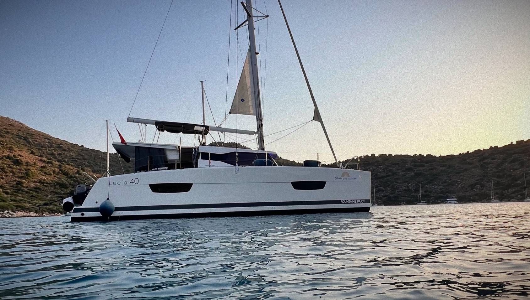 Катамаран Fountaine Pajot 40 «Dolce» на якоре в бухте на закате, рядом холмы