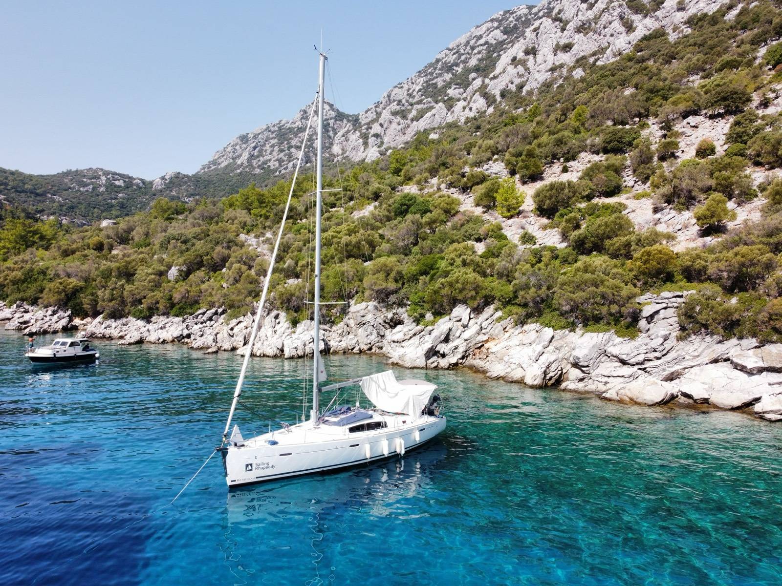 Яхта Beneteau Oceanis 43 «Rhapsody» на якоре у скалистого берега с соснами, бирюзовая вода