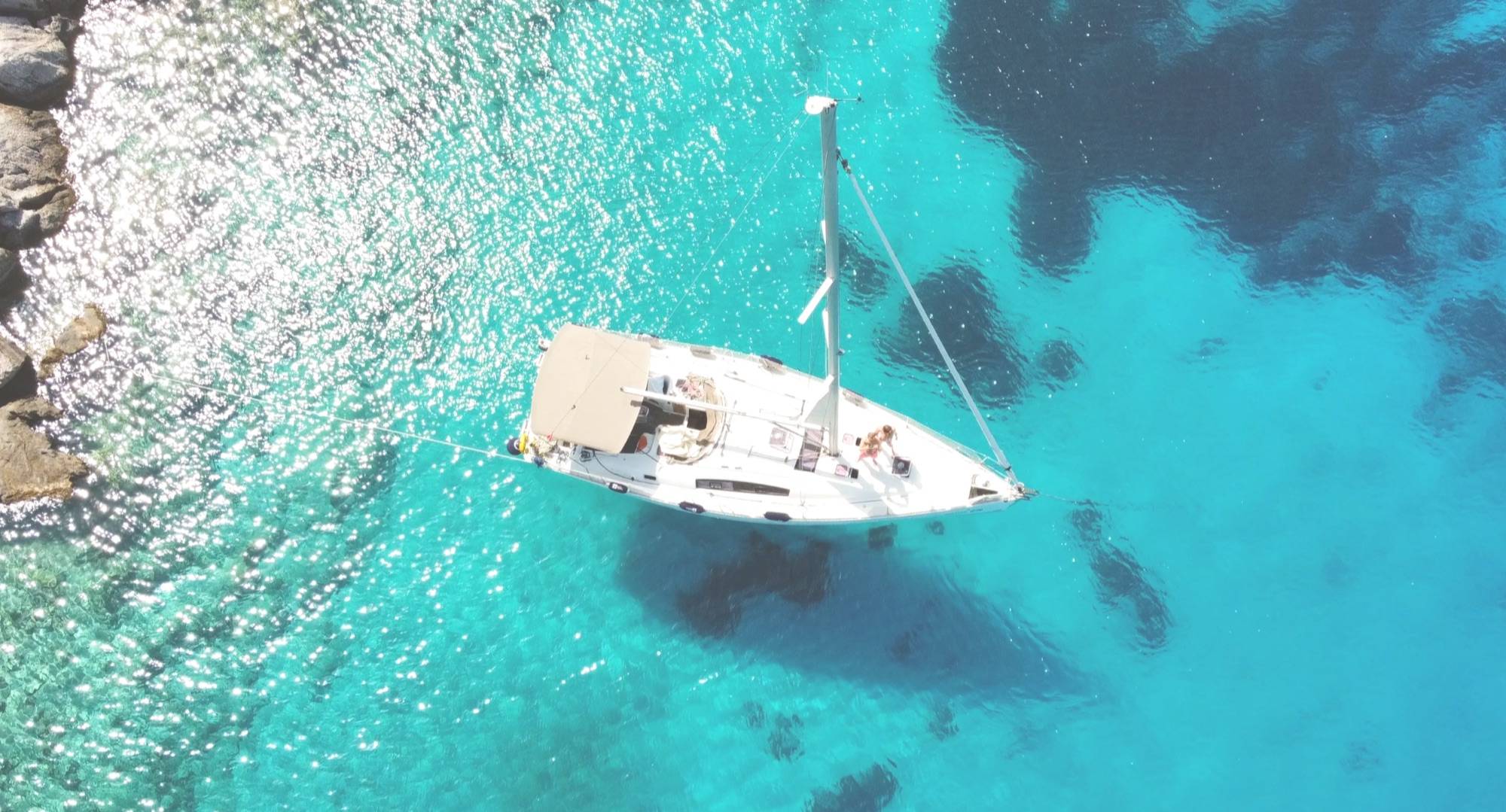 Вид сверху на яхту Beneteau Oceanis 40 «Arina» на якоре в бирюзовой воде у берега